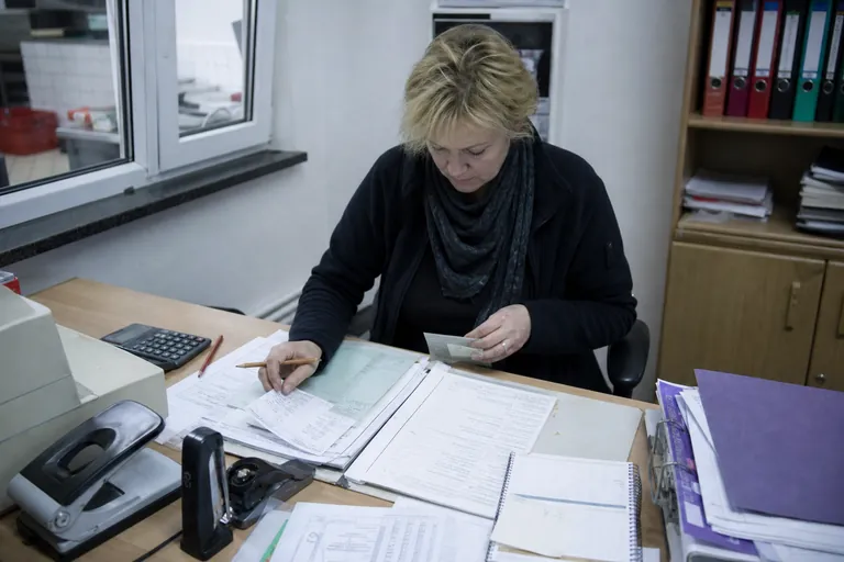Betriebsleiterin kalkuliert Arbeitszeit und Unterlagen für Personalbelehrungen.