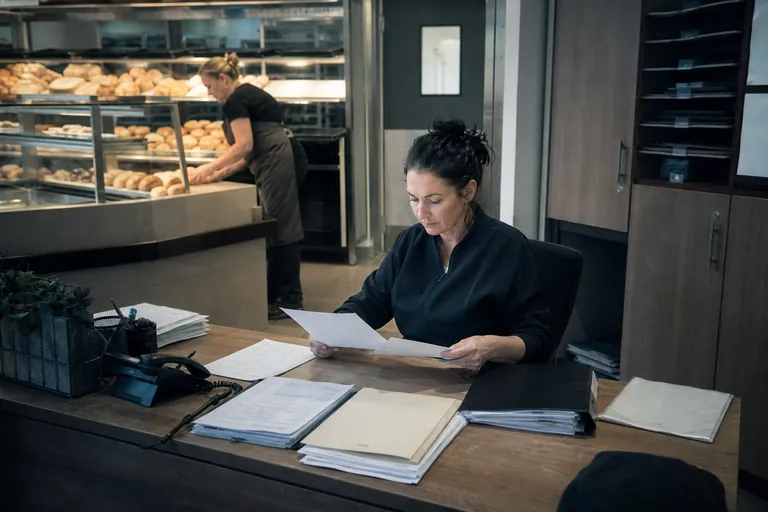 Filialleiterin prüft Personalunterlagen vor dem Einsatz neuer Mitarbeitender in einer Bäckerei.
